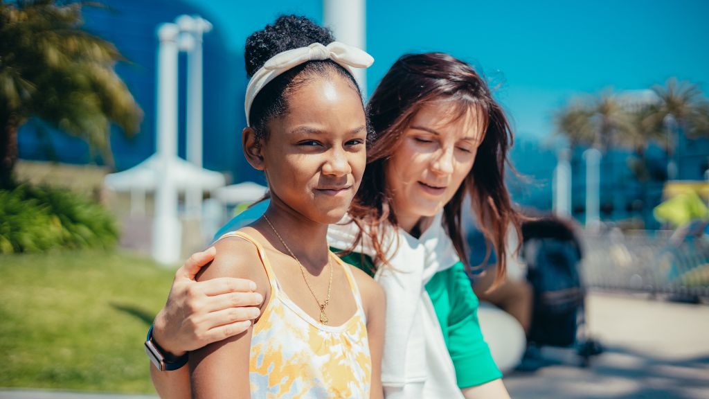 Woman has arm around girl